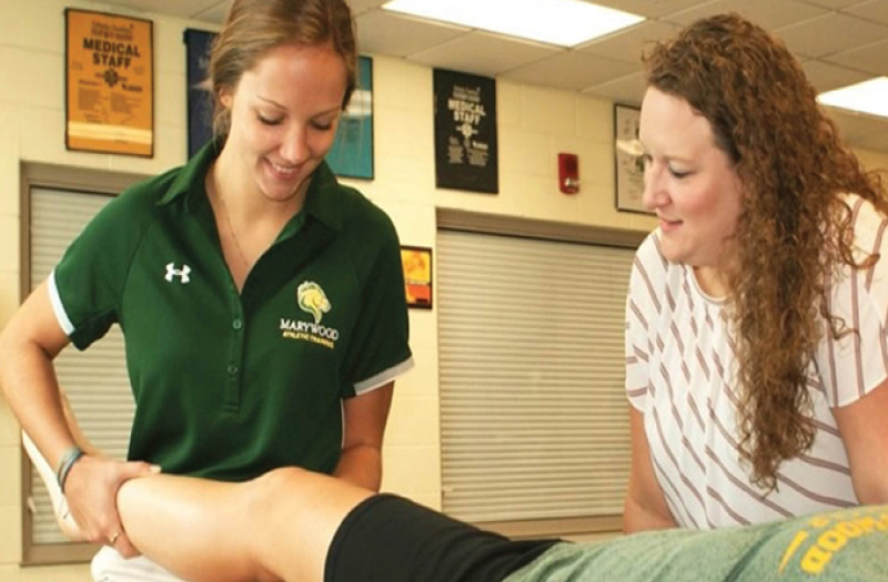 A female athlet trainer holding a patient's knee.